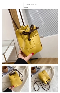 Detail of yellow woven leather bucket bag featuring drawstring bow and thin brown strap