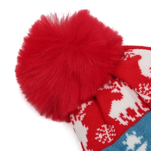 Detailed macro view of festive knit hat featuring a large red faux fur pom-pom and reindeer pattern