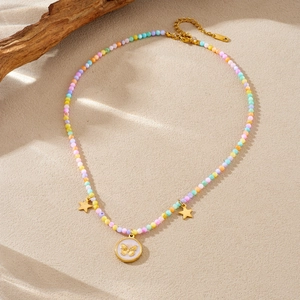 Collier de perles colorées avec pendentifs étoiles dorées et papillon sur surface texturée