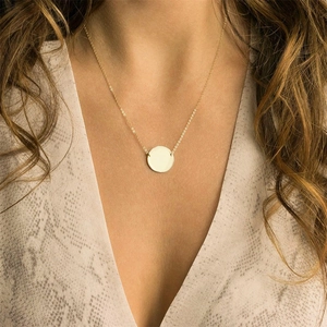 Close-up of minimalist gold circular pendant necklace on model with snakeskin pattern top