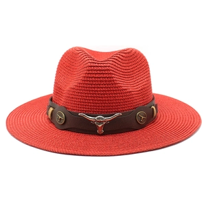 Detail of red straw fedora hat featuring a brown leather band and silver bull head emblem
