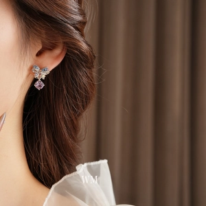 Elegant silver bow earrings with colorful crystal pendants worn by a model