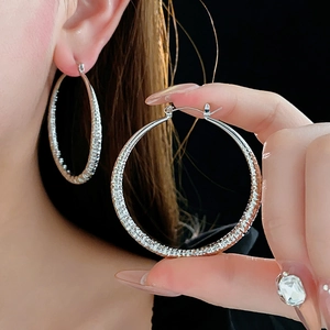 Détail de boucles d'oreilles créoles argentées texturées avec finition froissée en métal