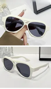 Detail shot of white aviator sunglasses with dark grey lenses and premium glossy frame