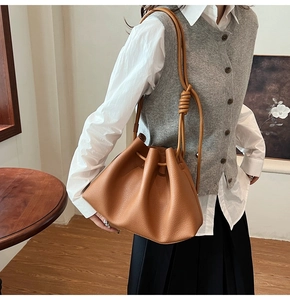 Brown pleated leather bucket bag with drawstring detail and knotted shoulder strap