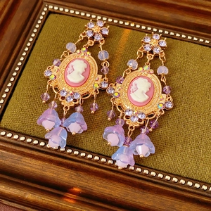 Close-up of vintage cameo earrings with purple crystal beads and floral fringe