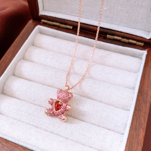 Detailed close-up of rose gold teddy bear pendant with pink crystals and red heart gem