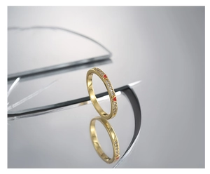 Macro shot of minimalist gold ring with red heart pattern and cubic zirconia on mirrors