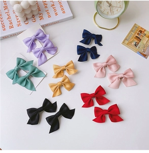 Set of 12 colorful satin bow hair clips for girls displayed on a white background