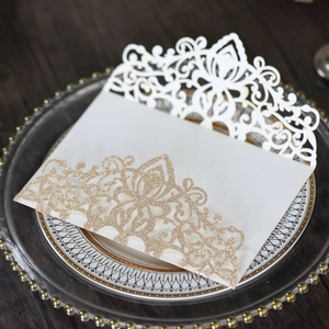 Detailed laser-cut white wedding invitation sleeve with golden glitter card insert