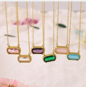 Detail shot of multicolor oval gemstone necklaces with gold chains on white fabric