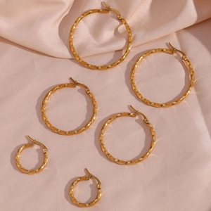 Three sizes of 18K gold plated stainless steel twisted hoop earrings on pink satin