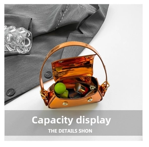 Detail of mini orange patent leather bag showing interior capacity for lipstick and perfume