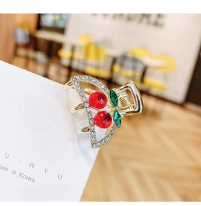 Close-up of cherry mini hair claw clip with red rhinestones and gold alloy frame