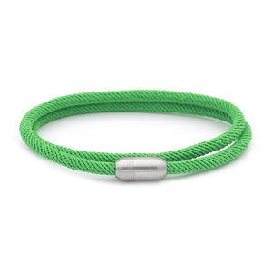 Detail of green woven cord bracelet featuring a cylindrical silver magnetic clasp closure