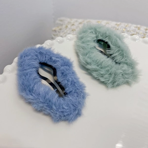 Chic plush faux fur cloud hair clips in blue and green on a white textured plate