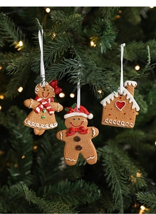 Gingerbread man and house resin charms hanging on a Christmas tree with warm lights