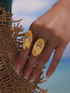 Close-up of golden geometric ring with white pearls and textured radial metal design