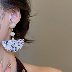 Detail of vintage fan-shaped earrings with floral pattern and resin pearls for women