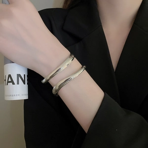 Macro detail of silver geometric wave bangle showing glossy metallic texture on wrist