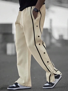Detail of beige joggers featuring side black stripes and functional snap button closures