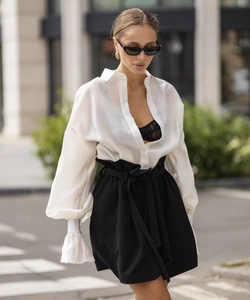Close-up of white flared sleeve shirt and high waist tied black trousers set