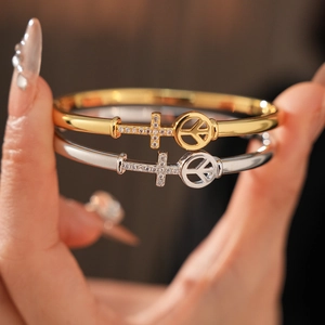 Detail of gold and silver bangles with cross and peace symbols showing micro-pave setting