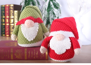 Close-up of handmade knitted Christmas gnomes in red and green with festive holiday decor