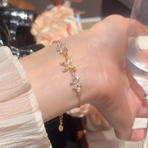Detail of 18k gold plated flower butterfly bracelet with zircons on female wrist