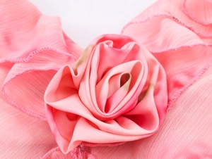 Makro-Detail einer zartrosa Chiffon-Rose mit schichtweisen Blütenblättern aus Stoff