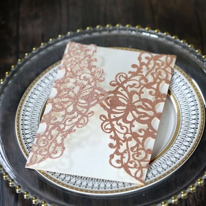 Close-up of rose gold glitter laser-cut wedding invitation with intricate floral details