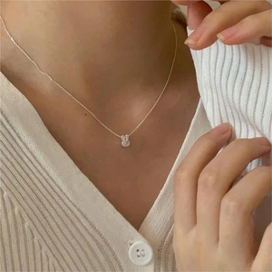 Close-up of a silver bunny pendant necklace worn by a model on a white knit sweater