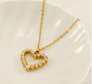 Close-up of gold heart pendant necklace with rhinestones on a white shell tray