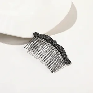 Detail shot of wavy black crystal hair comb with dense metal teeth on a white plate
