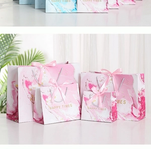 Detail of pink marble gift bags with gold Happy Times text and satin ribbon handles