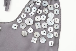 Détail de boutons en nacre blanche cousus sur le tissu gris d'une robe d'été