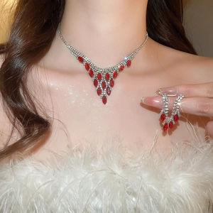 Close-up of elegant silver necklace and red marquise crystal earrings worn by model