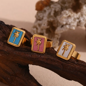 Macro detail of square rings with golden palm trees on colorful shells at the beach