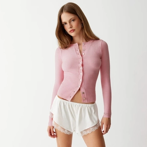 Detail of pink ribbed knit cardigan with pearl buttons and white lace-trimmed silk shorts