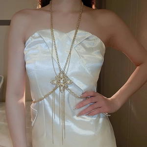 Detail of gold body chain featuring pearl and rhinestone cross pendant with tassels