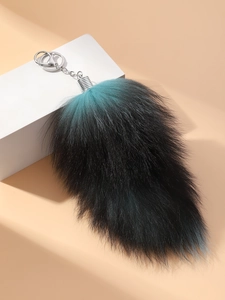 Detailed close-up of blue and black gradient faux fur fox tail keychain on white prop