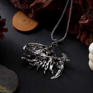 Gros plan détaillé du pendentif faucheuse en argent avec ailes et faux sur bois sombre