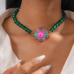 Détail d'un collier bohème avec perles de cristal vertes et pendentif fleur dorée