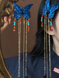 Détail de la pince à cheveux papillon brodé bleu avec d'élégants longs glands dorés