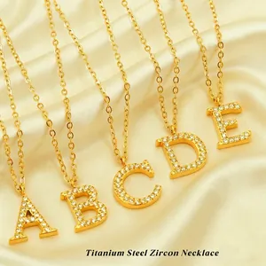 Golden titanium steel alphabet necklaces with zircon pendants on yellow silk background
