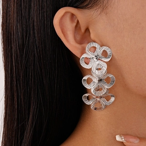 Close-up of silver triple hollow flower drop earrings with striped metallic texture