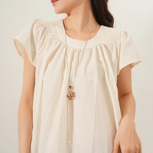 Dettaglio della collana con pendente a orso e catena argentata su maglione beige