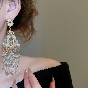 Detail of luxury crystal chandelier earrings with pearl tassels on a model