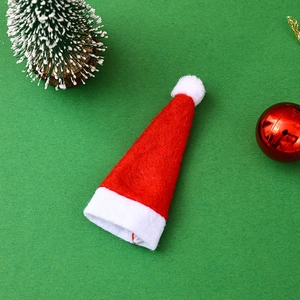 Close-up of mini red and white plush Christmas hat for wine bottles and cutlery decor