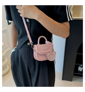 Pink mini crossbody bag with a cute bear charm shown on a black outfit for styling